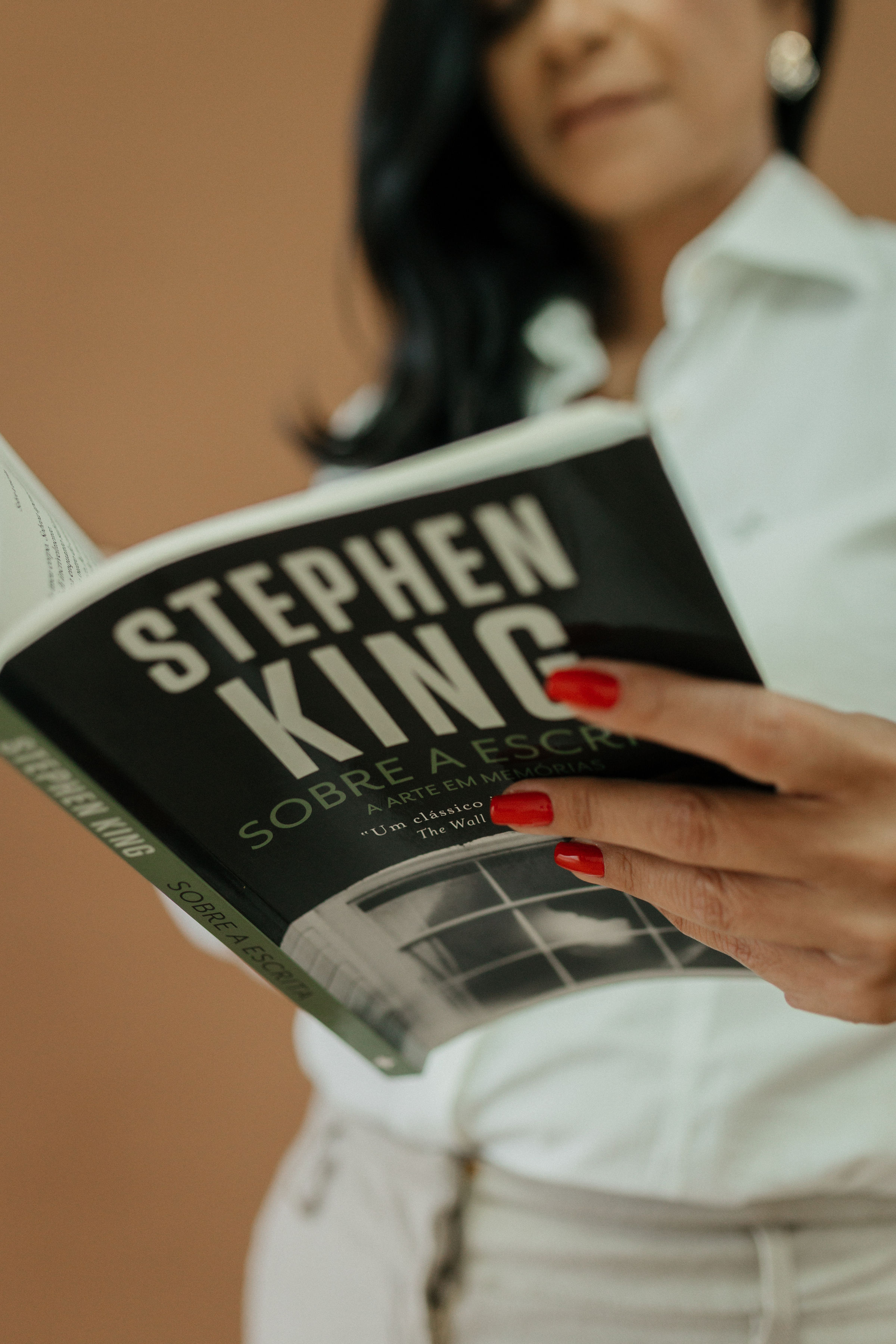 Detalhe das mãos de Ana Lígia lendo livro Sobre a Escrita