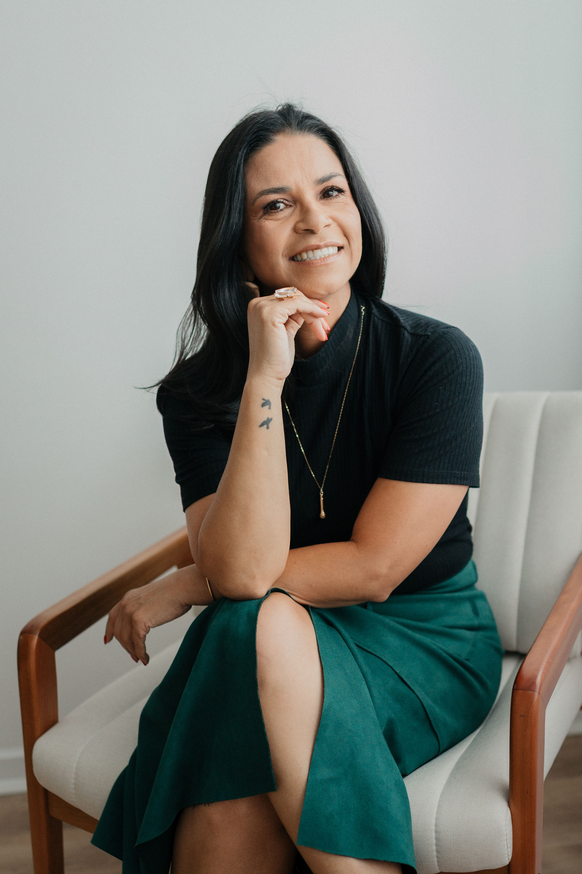 Ana Lígia Sena sentada sorrindo com confiança durante ensaio editorial